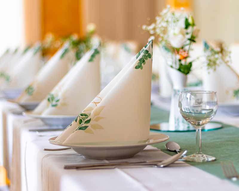 Festlich gedeckter Tisch mit gefalteten Servietten, Gläsern und Besteck