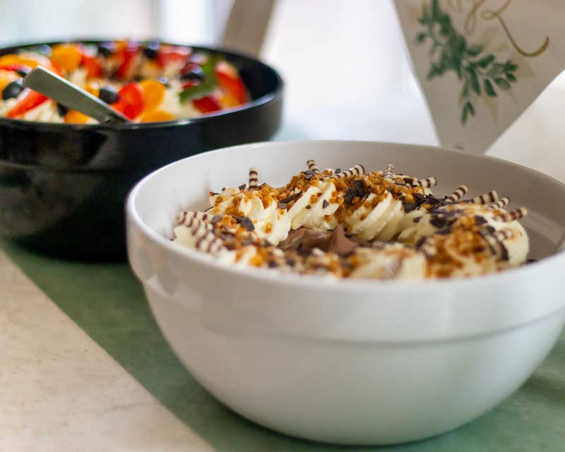 Landingpage Rheiderland 4 Zwei Schüsseln mit Dessert, vorne mit Sahne und Schokostreuseln, hinten Obstsalat